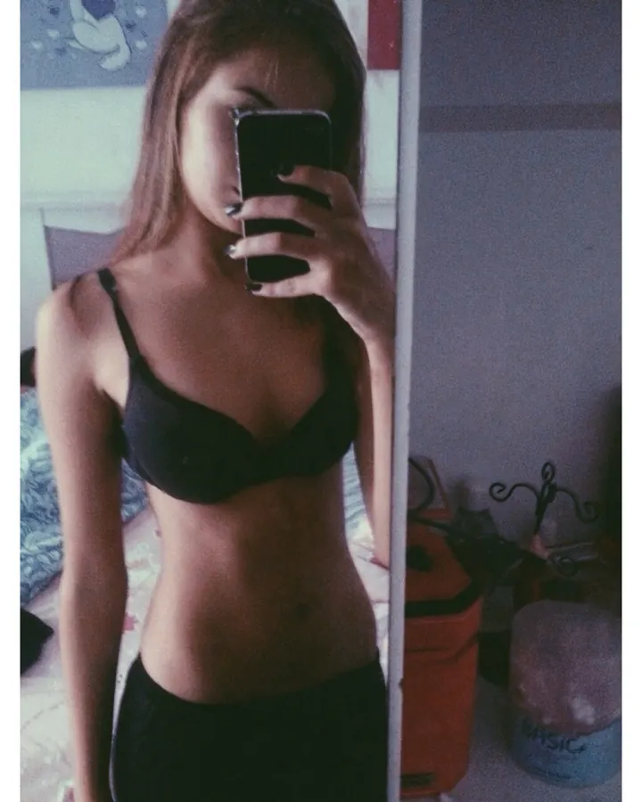 Jeune femme brune en soutien-gorge noir, selfie miroir dans une chambre