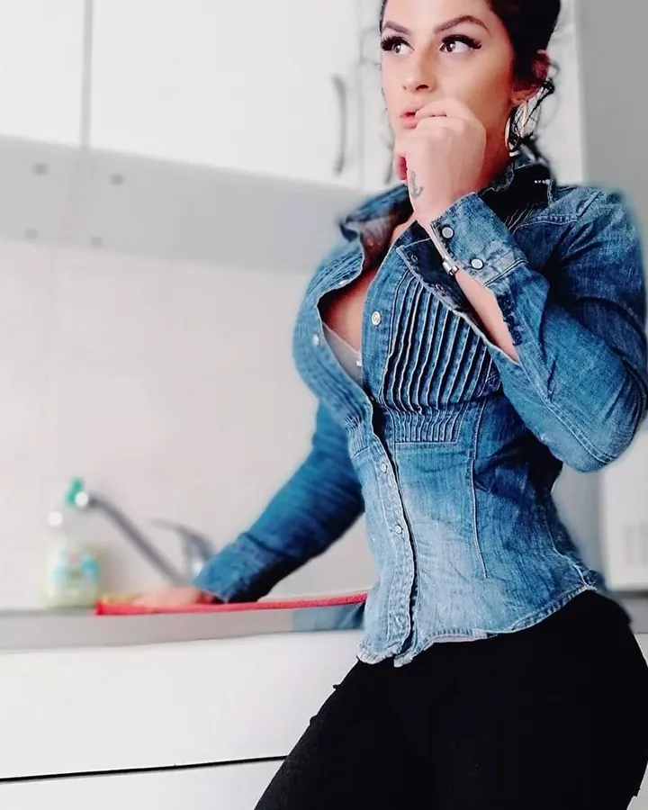 Jeune femme brune en chemise en jean, regard vers le haut, main près du visage