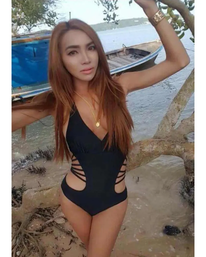Femme en tenue jaune, souriante, assise sur un banc, avec une lumière chaude en arrière-plan.