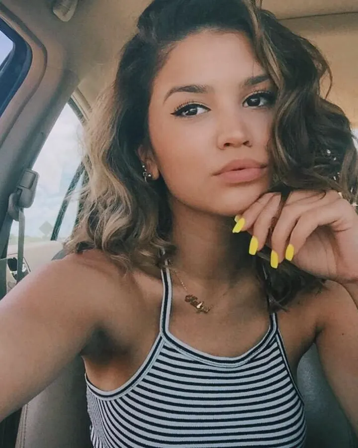 Jeune femme latine en tenue bleue, souriante en extérieur