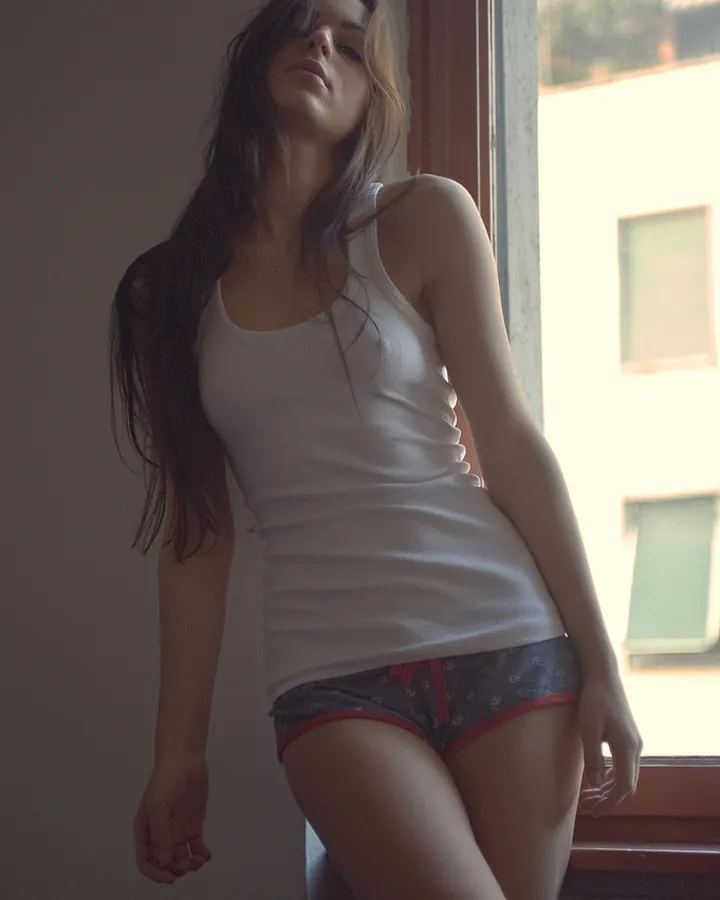 Femme aux cheveux châtains en short en jean, prenant un selfie nu torse devant un miroir.