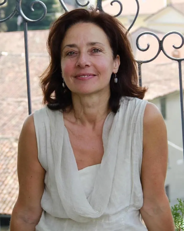 Femme en haut noir, cheveux bruns, souriant dans un salon