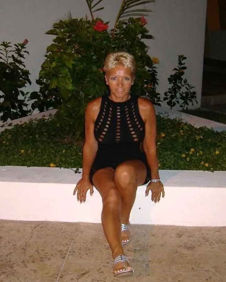 Femme en haut rouge, cheveux longs noirs, regardant l'appareil photo dans une salle de bain