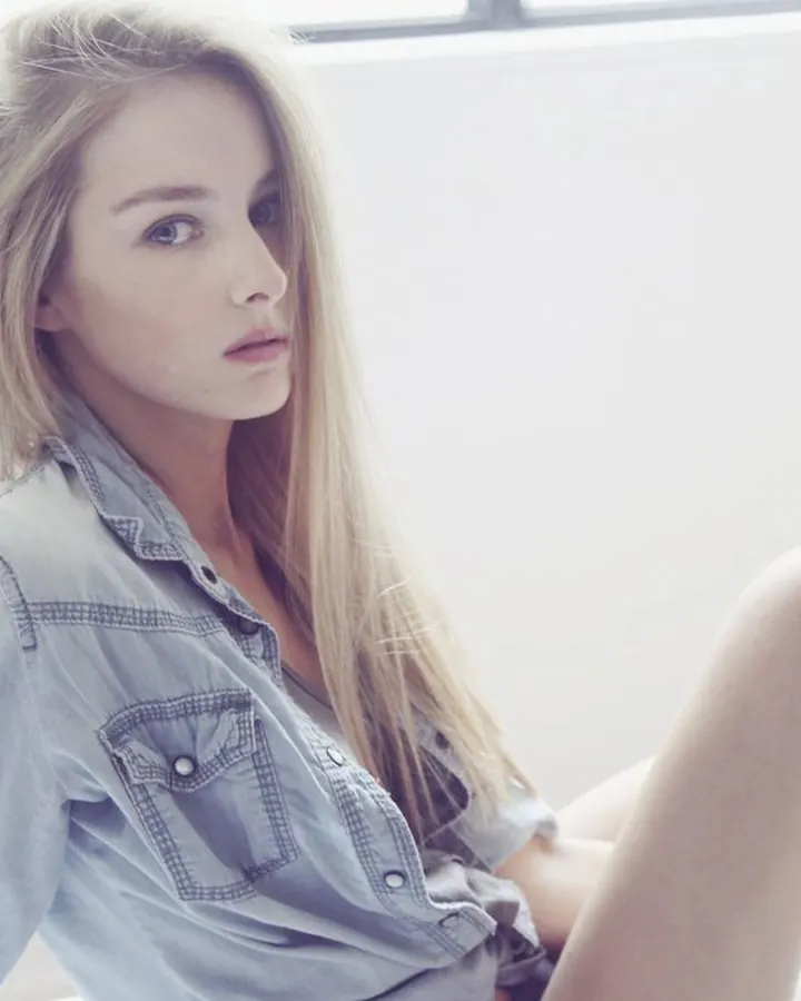 Émilie blonde assise en chemise denim, regard caméra