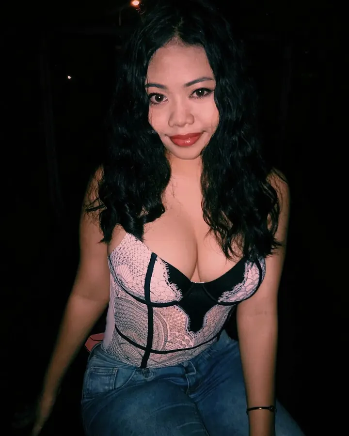 Femme asiatique en bustier rose et jean, regard vers l’appareil.