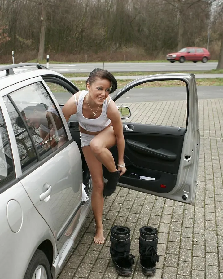 Jeune femme aux cheveux foncés en haut blanc, short blanc, sortant d’une voiture blanche, pieds nus.