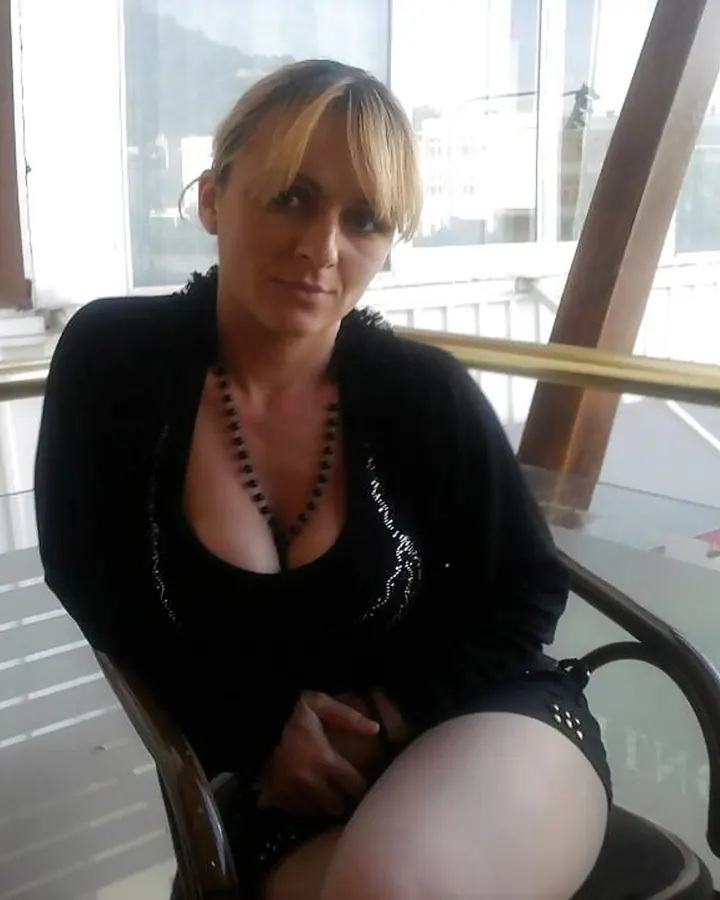 Femme en tenue blanche, assise à une table de café, portant des lunettes de soleil