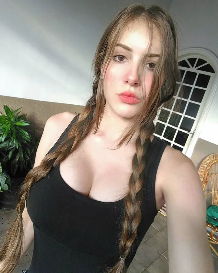 Femme blonde, yeux marrons, en haut noir, regardant l'objectif avec une expression sereine.