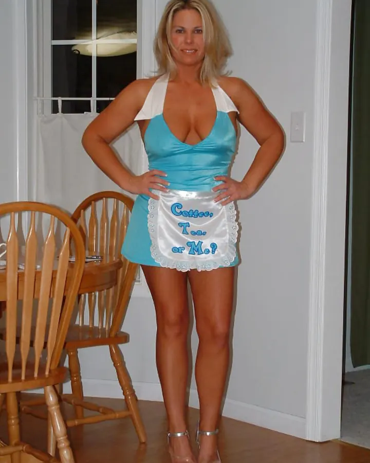 Femme blonde, yeux bleus, en haut blanc, regardant l'objectif avec un sourire discret.